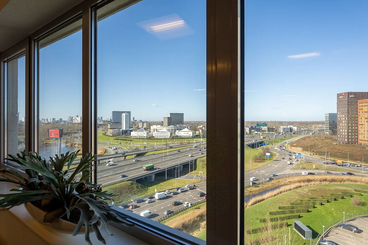 Uitzicht vanuit een kantoorgebouw in Rivium Quadrant op snelwegen, kantoorpanden en de skyline van Rotterdam.